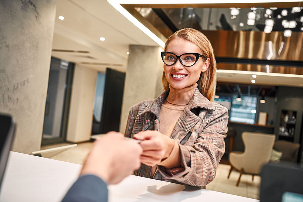 Young woman in hotel check in at reception or front office being given key card business travel and accommodations