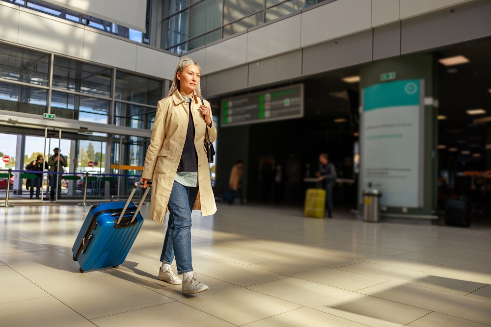 Female traveler carrying trolley luggage bag at airport Woman in the airport with trolley traveling for business during thanksgiving travel