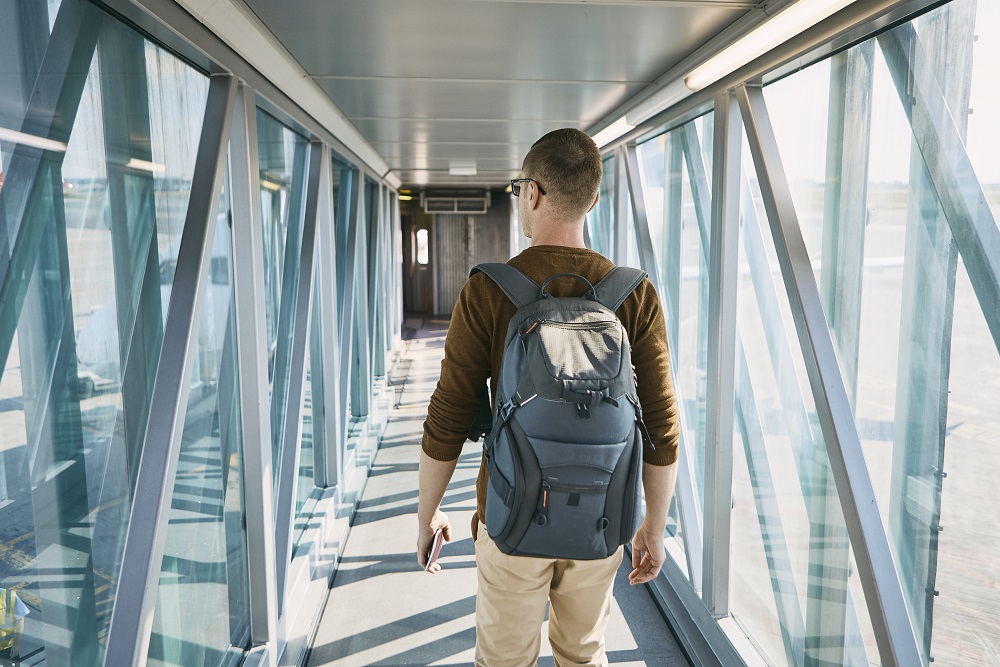 Boarding to airplane Business traveler walking down jet bridge to airplane with backpack