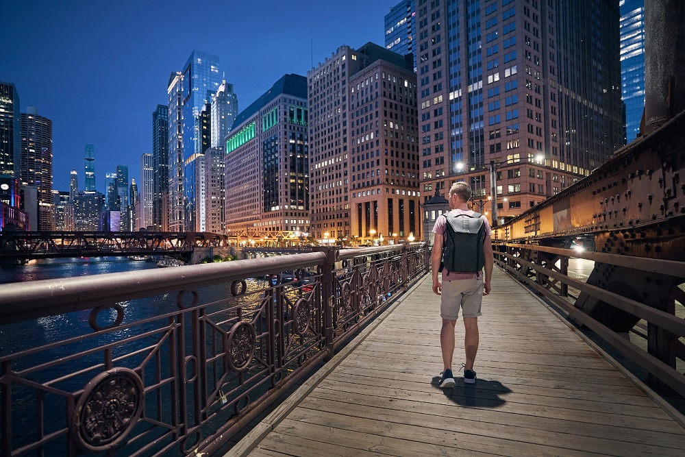 Man with backpack while walking on bridge in Downtown Chicago Man on Chicago river walk by night