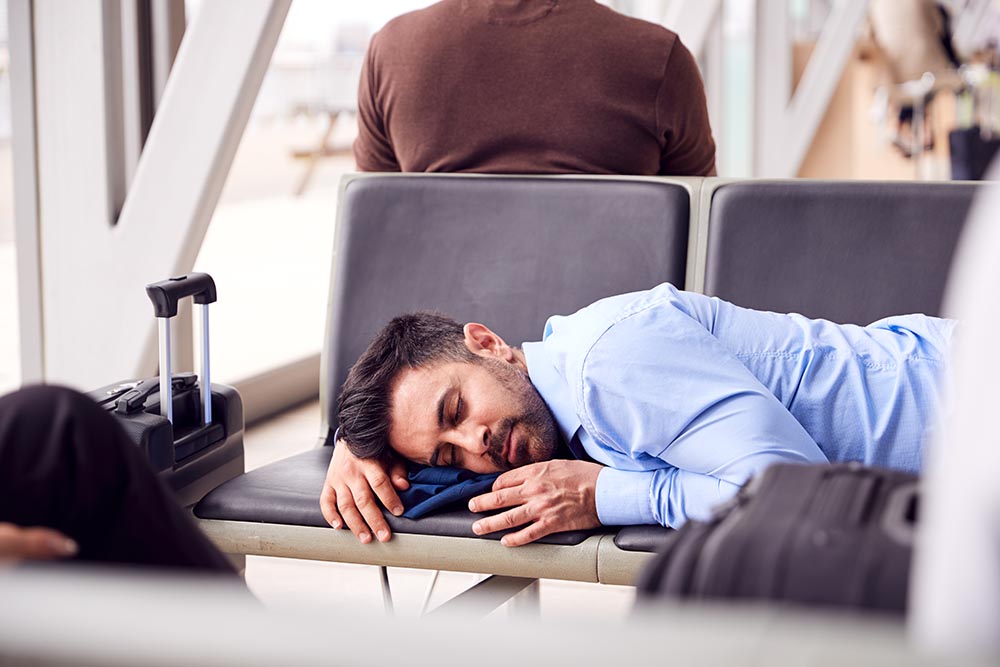 Businessman Sleeping On Seats In Airport Departure Lounge Because Of Delay Man in business clothes sleeping on airport chairs on a layover