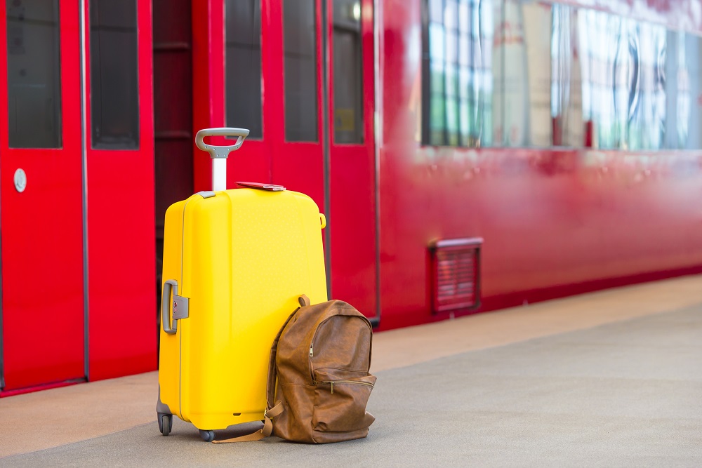 Yellow luggage with passports and brown backpack at train station Gepäck