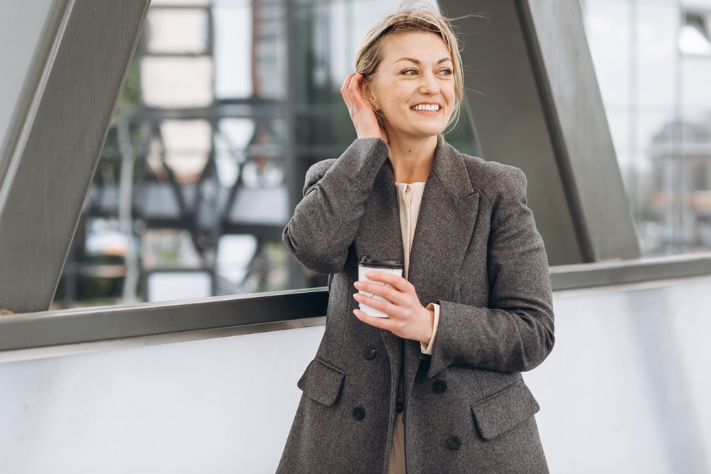 Portrait of a mature business woman smiling with emotions and dr Geschäftsfrau mit Kaffee zu Fuß außerhalb