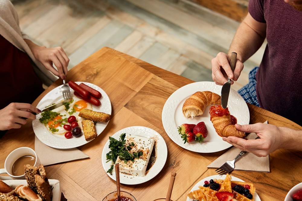 Close-up of couple eating breakfast at dining table. Business people eating a hotel continental breakfast