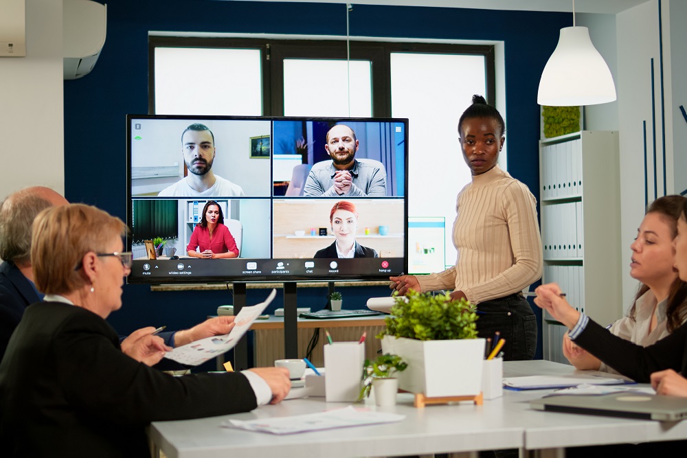 Black manager woman talking with remotely colleagues on video call Hybrid meeting with woman leading in a conference room