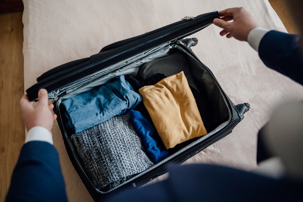 Crop businessman packing clothes for trip Packen Sie für eine Geschäftsreise ein