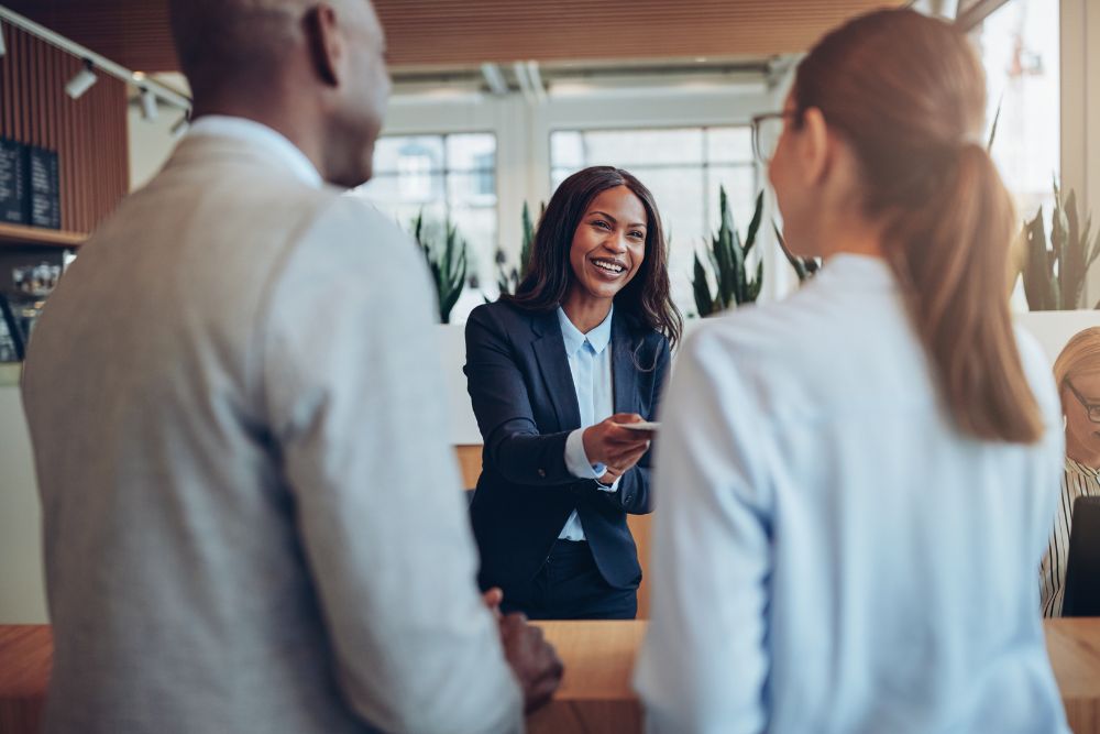 group booking Two business travelers at the front desk of a hotel. Receptionist giving them back their documentation for the group booking.
