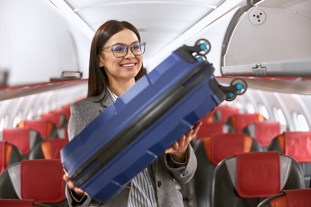 Happy caucasian female passenger with luggage in airplane salon Handgepäck