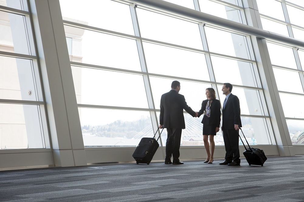 USA,Three business people meeting in front of a large window in a conventnion center lobby. corporate travel procurement