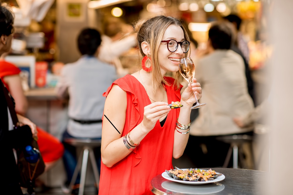 Woman eating mussels at the food market Woman eating mussels standing in a food market in Madrid